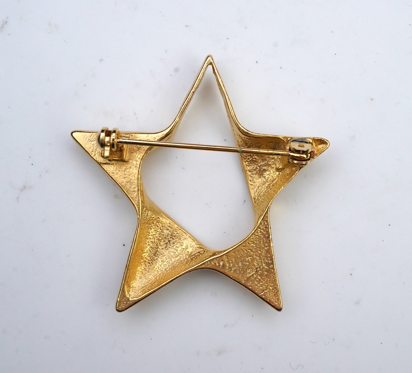 A tarnished gold star brooch in box